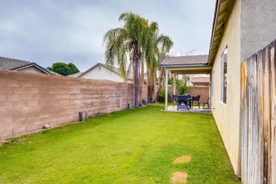 a yard with a brick wall and palm trees at 8 Mi to Beach Park Bakersfield Gem with Yard! in Bakersfield