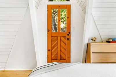 a bedroom with a wooden door in a attic at Luxury A-Frame Retreat in Lake Arrowhead