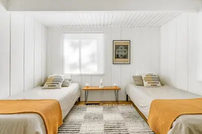 a white room with two beds and a table at Luxury A-Frame Retreat in Lake Arrowhead