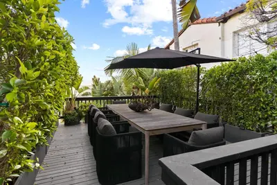 a wooden table with chairs and an umbrella on a deck at Hollywood Hills 3 Bedroom Views and Jacuzzi in Los Angeles