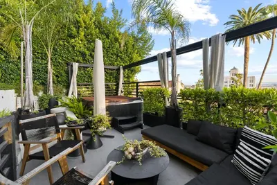 a patio with a black couch and a table and chairs at Hollywood Hills 3 Bedroom Views and Jacuzzi in Los Angeles