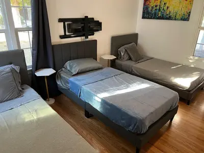 a bedroom with two beds and a cross on the wall at Modern piano Los Angeles home by universal studio & Hollywood for 10 in Studio City