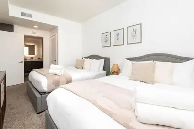 two beds in a bedroom with white walls at Hollywood Cozy Apartment in Los Angeles