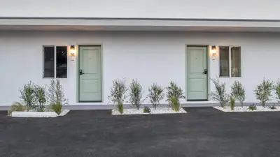 a white building with green doors and potted plants at The LEEF Hotel in Glendale