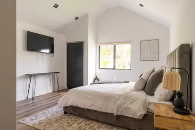 a white bedroom with a large bed and a television at Tulum Style in Sherman Oaks in Garnsey