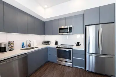 a kitchen with blue cabinets and a stainless steel refrigerator at Designer 1 Bedroom Condo in Prime Hollywood in Los Angeles