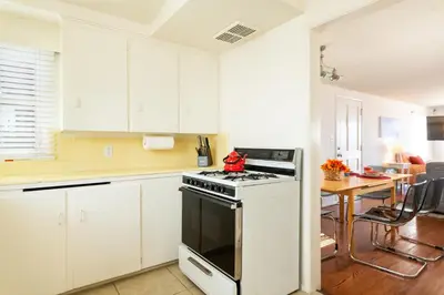 a kitchen with white cabinets and a stove and a table at The Sea View Inn At The Beach in Manhattan Beach