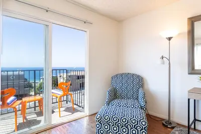 a living room with a chair and a balcony at The Sea View Inn At The Beach in Manhattan Beach