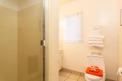 a bathroom with a shower and a toilet and towels at The Sea View Inn At The Beach in Manhattan Beach