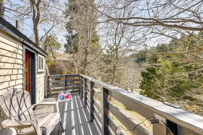 a rocking chair sitting on the porch of a house at Tiny Home with Deck and Mtn Views in Lake Arrowhead! in Lake Arrowhead