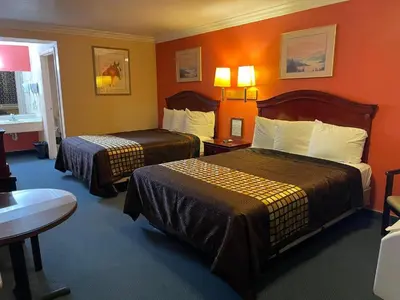 a hotel room with two beds and orange walls at Aerospace Inn in Mojave