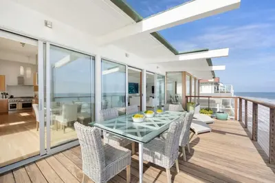 a dining room with a table and chairs on a balcony at Malibu Cove Colony Beach by Stay Awhile Villas in Malibu