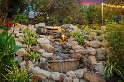 a garden with a waterfall in the middle of rocks at Sunny Getaway and 10 Min to SB in Summerland