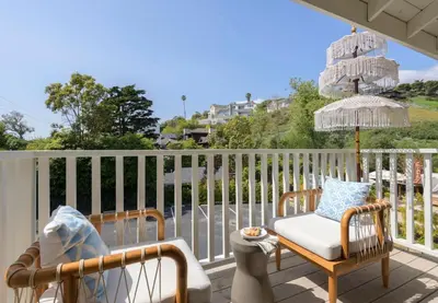 a porch with two chairs and an umbrella at Sunny Getaway and 10 Min to SB in Summerland