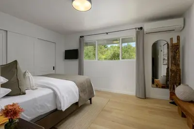 a bedroom with a bed and a large window at Private Balcony and Coastal Escape in Summerland