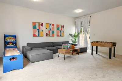 a living room with a gray couch and a video game at Vintage Vibes Near Airport Games Sleeps 8 in Long Beach