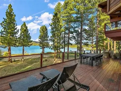 a deck with a table and chairs and a view of the water at Bear Lake Lodge Lakefront Incredible Lake House Chalet in Big Bear Lake