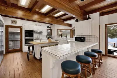 a kitchen with white cabinets and a large island with bar stools at Bear Lake Lodge Lakefront Incredible Lake House Chalet in Big Bear Lake