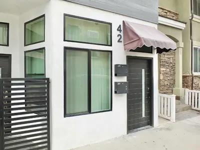 a white building with a black door and an awning at Beach & Bay Retreat - Full of Amenities in Long Beach