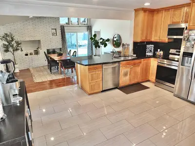 a large kitchen with wooden cabinets and a dining room at Bellflower Breeze - Charming 3 BDR in Long Beach in Long Beach