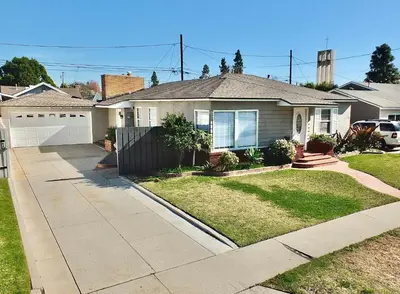 a house with a driveway in a residential neighborhood at Bellflower Breeze - Charming 3 BDR in Long Beach in Long Beach