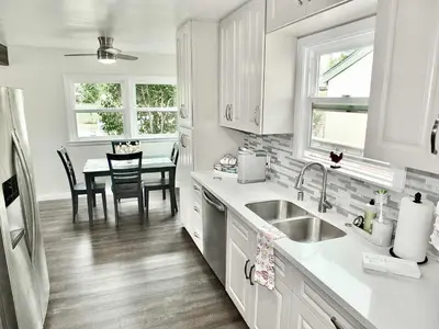 a kitchen with white cabinets and a dining table at Greenbelt Guesthouse - Unlimited Peace & Privacy Golf Bowling Green & More in Long Beach
