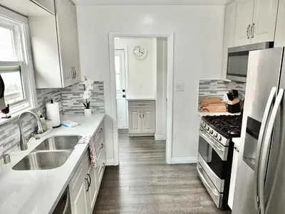 a white kitchen with a sink and a stove at Greenbelt Guesthouse - Unlimited Peace & Privacy Golf Bowling Green & More in Long Beach