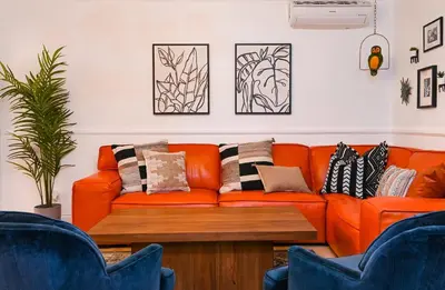 an orange couch in a living room with pillows at Immaculate 3BDR Bungalow - 5-Min Walk to Beach in Long Beach