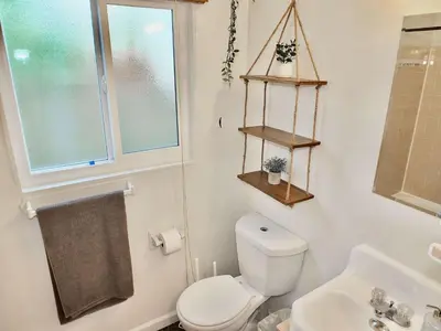 a bathroom with a toilet and a sink and a window at Sand Sun & Second - Charming Studio within Walking Distance to Beach in Long Beach