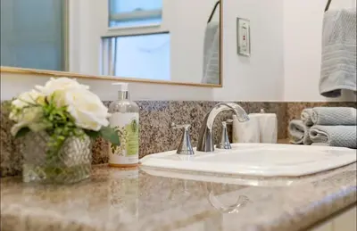 a bathroom counter with a sink and a vase of flowers at Steps to Sand Cozy 3BR Partial Ocean Views in Manhattan Beach