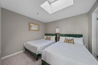 two beds in a room with white walls at Ocean Views - Rooftop Pool 2BR Santa Monica in Los Angeles