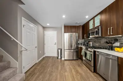 a kitchen with stainless steel appliances and wooden cabinets at Ocean Views - Rooftop Pool 2BR Santa Monica in Los Angeles