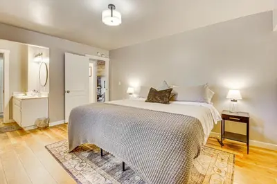 a bedroom with a large bed and a bathroom at 2 Mi to Lake Arrowhead Treetop Retreat with Deck in Lake Arrowhead