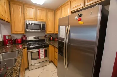 a stainless steel refrigerator in a kitchen with wooden cabinets at Radiator Springs by Funtierland Vacation Rentals in Anaheim