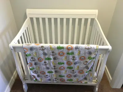 a white crib with a patterned blanket on it at Arendelle by Funtierland Vacation Rentals in Anaheim