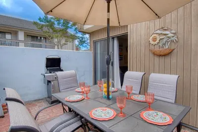 a table with glasses and an umbrella on a patio at Maleficents Retreat by Funtierland Vacation Rentals in Anaheim
