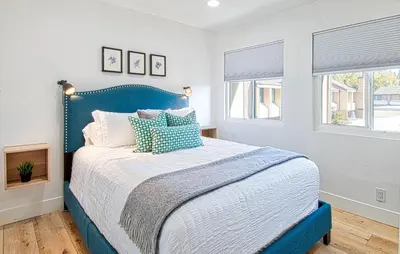 a blue bed in a bedroom with two windows at New Suite Escapes 5 by Funtierland Vacation Rentals in Anaheim