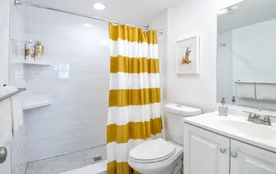 a bathroom with a toilet and a yellow shower curtain at New Suite Escapes 6 by Funtierland Vacation Rentals in Anaheim