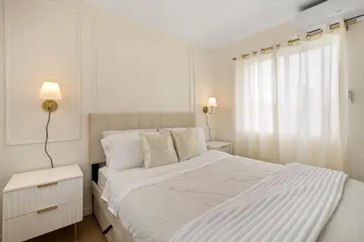 a white bedroom with a large bed and a window at Hollywood Glam Hideaway - Steps to Walk of Fame in Los Angeles