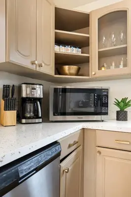 a kitchen with white cabinets and a black microwave at Hollywood Glam Hideaway - Steps to Walk of Fame in Los Angeles