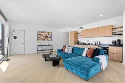 a living room with a blue couch and a kitchen at Rooftop Pool Modern 2BR, 2BA - Panoramic Hollywood views in Los Angeles