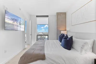 a white bedroom with a large bed with blue pillows at Rooftop Pool Modern 2BR, 2BA - Panoramic Hollywood views in Los Angeles