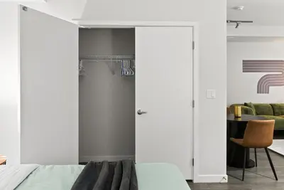 a bedroom with white walls and a bed and a chair at Spacious and Bright West Hollywood Pool & Gym in Los Angeles