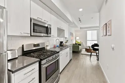 a kitchen with a stove top oven next to a living room at Spacious and Bright West Hollywood Pool & Gym in Los Angeles