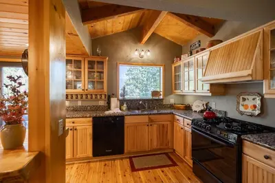 a kitchen with wooden cabinets and black appliances at Ultimate Lakeview Lodge and ON THE LAKE! with a Hot-Tub! in Big Bear Lake
