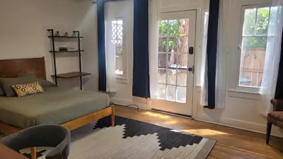 a bedroom with a bed and two windows with blue curtains at Charming Studio Four with Private Patio in Los Angeles