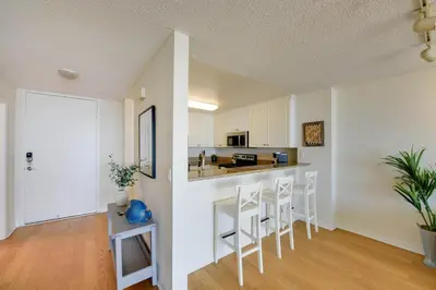 a kitchen with white cabinets and white stools at Oceanfront Bliss, Beach & Marina Views, Roomy 1BR in Los Angeles