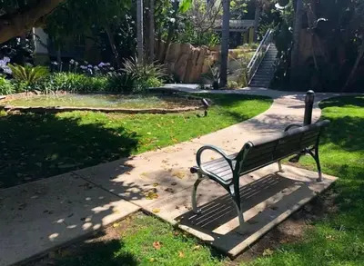a park bench sitting on a sidewalk in the grass at Oceanfront Bliss, Beach & Marina Views, Roomy 1BR in Los Angeles