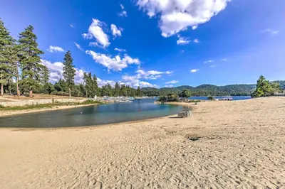 a sandy beach next to a body of water at Walk to Lake Arrowhead Village Gem with Lake Access in Lake Arrowhead