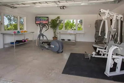 a gym with treadmills and machines in a room at Bella Vista by Paradise Retreats in Carpinteria
